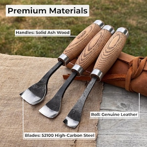 May include: Three wood carving chisels with solid ash wood handles and 52100 high-carbon steel blades. The chisels are displayed on a tan surface with a brown leather roll. The text "Premium Materials" is at the top.