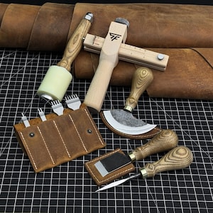 Puede incluir: Un conjunto de herramientas para trabajar el cuero que incluye un mazo de madera, un cortador de correas con marcas métricas, un cuchillo de media luna, un cuchillo de rebajar, un punzón y un estuche de cuero marrón con cuatro cinceles.