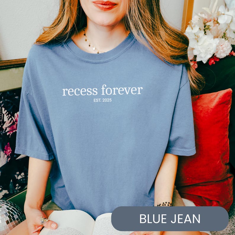 Op de afbeelding: Een jeansblauw t-shirt met de tekst "recess forever est. 2025" gedrukt op de voorkant.