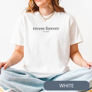 Op de afbeelding: Wit T-shirt met de tekst "recess forever est. 2025" gedrukt op de voorkant.
