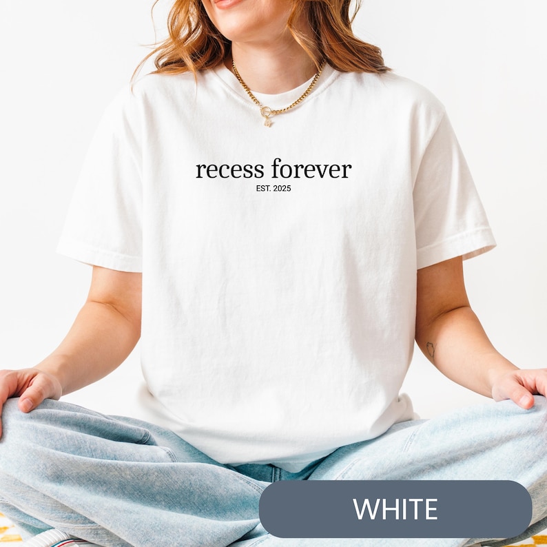 Op de afbeelding: Wit T-shirt met de tekst "recess forever est. 2025" gedrukt op de voorkant.