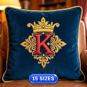 Pode incluir: Uma almofada de veludo azul marinho com acabamento dourado e uma coroa e enfeites dourados bordados. A letra "K" vermelha está centrada sob a coroa. A almofada está em uma cadeira de couro marrom. O texto "15 SIZES" está na parte inferior.