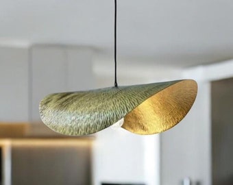 May include: A modern pendant light fixture with two overlapping, curved shades. The shades are a textured gold colour on the outside and a green colour on the inside.