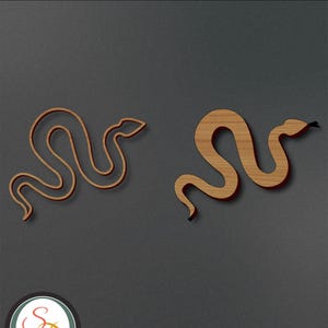 Op de afbeelding: Twee houten slangen-uitsnijdingen, een met een traditionelere slangvorm en de andere met een meer gestileerde slangvorm. De slangen zijn beide bruin en hebben een houtnerfstructuur.