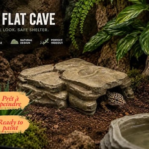 Puede incluir: Un refugio para reptiles de textura rocosa en color beige, etiquetado como BIG FLAT CAVE con el texto NATURAL LOOK. SAFE SHELTER. Un pequeño gecko leopardo moteado es visible en la entrada. La imagen incluye el texto Prêt à peindre y Ready to paint.