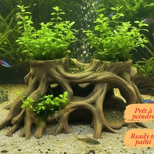 Op de afbeelding: Een bruin aquariumornament van hars in de vorm van een boomstronk met blootliggende wortels en twee holle toppen met groene waterplanten. Het ornament bevat twee oranje labels met de tekst "Prêt à peindre" en "Ready to paint".