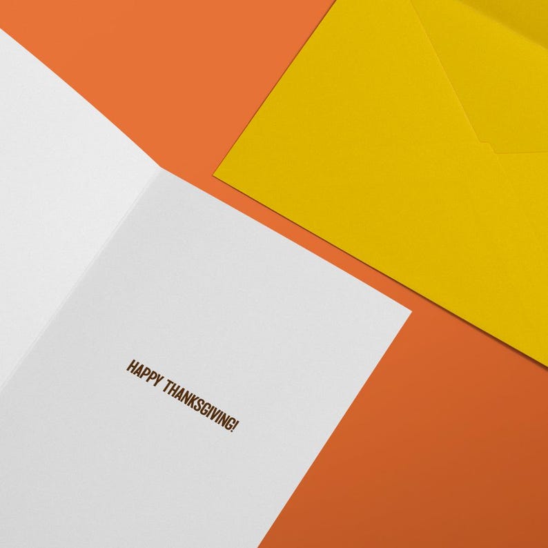 Puede incluir: Una tarjeta de felicitaci&oacute;n blanca con el texto HAPPY THANKSGIVING! impreso en tinta marr&oacute;n en el interior, acompa&ntilde;ada de un sobre amarillo s&oacute;lido, todo colocado sobre un fondo naranja vibrante para crear una presentaci&oacute;n festiva.