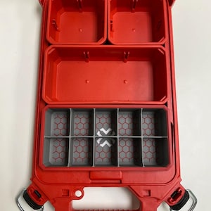 May include: Red plastic storage box with a clear lid and multiple compartments. The box has a handle and a latch. The compartments are divided into different sizes. The bottom compartment has a honeycomb pattern.