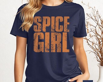 May include: Navy blue t-shirt with the words "SPICE GIRL" in distressed orange lettering. The shirt is a crew neck and short-sleeved. The text is centered on the front of the shirt. The shirt is made of a soft material.