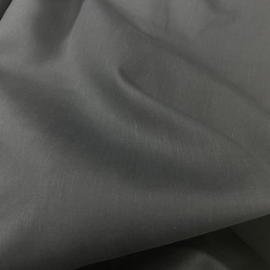 May include: A close-up of a dark gray fabric with a smooth, slightly textured surface.