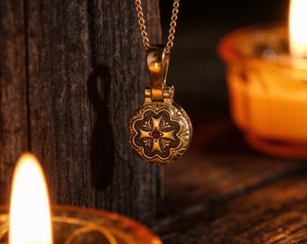 May include: A gold-toned circular pendant necklace featuring an embossed cross design with a small red stone at the center. The pendant hangs from a delicate gold-toned chain, showcasing intricate metalwork and a polished finish on the bail.