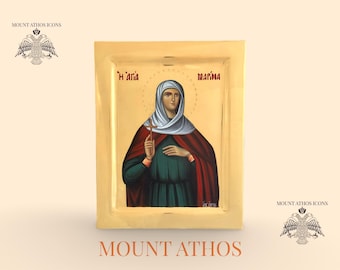May include: Hand-painted icon of a saint, featuring a woman in a green dress and red cloak, holding a cross. The icon has gold accents and the text "Mount Athos Icons" is displayed.