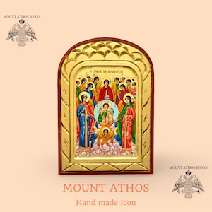 May include: A hand-made Mount Athos icon featuring a religious scene with figures in colorful robes. The icon has a gold-colored frame with a decorative border and a dark brown wooden base. The text "MOUNT ATHOS" and "Hand made Icon" are visible.