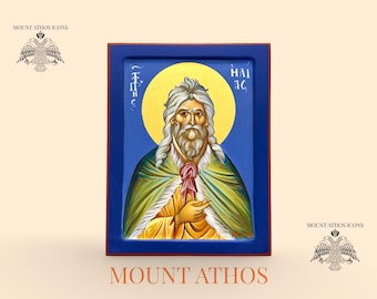 May include: Hand-painted icon featuring a saintly figure with long white hair and beard, set against a gold halo and blue background. The icon is framed in a dark blue border, with text at the bottom reading "MOUNT ATHOS" and "Hand painted Icon".