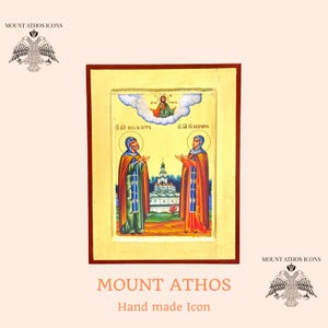 May include: Hand-painted icon depicting two figures in prayer, with a figure in a cloud above them. The icon is framed in a wooden frame with a gold background. The text "MOUNT ATHOS" is written below the icon.
