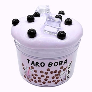 Lavender glossy slime in a clear jar labeled “Taro Boba,” topped with realistic ice cube charms, black boba ball charms, and a mini boba cup. Soft, thick texture and smooth finish, perfect for ASMR and bubble pops. Suitable for slime enthusiasts, collectors, and sensory play lovers.