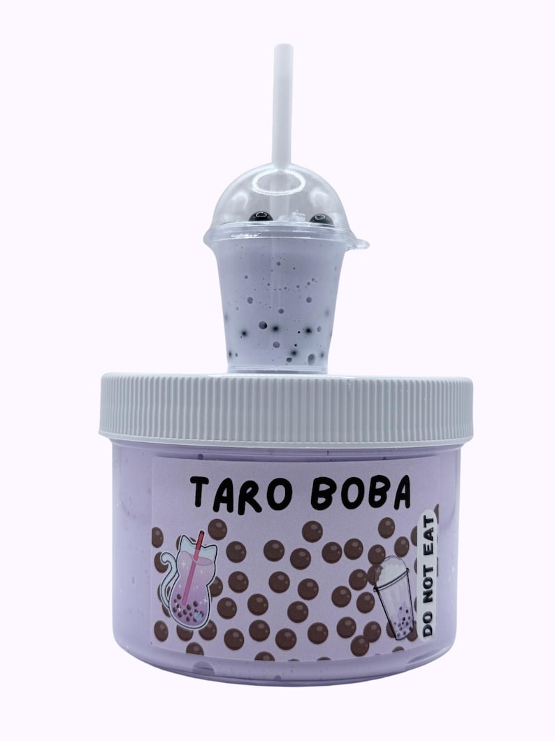 Lavender glossy slime in a clear jar labeled “Taro Boba,” topped with realistic ice cube charms, black boba ball charms, and a mini boba cup. Soft, thick texture and smooth finish, perfect for ASMR and bubble pops. Suitable for slime enthusiasts, collectors, and sensory play lovers.