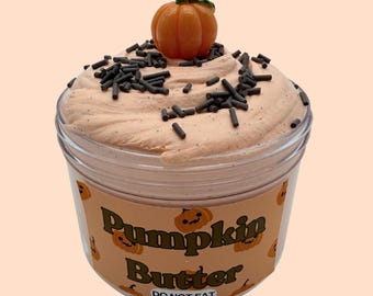 May include: A clear plastic jar filled with light orange textured slime topped with dark brown sprinkles and a small orange pumpkin charm. The label features repeating pumpkin illustrations and the text Pumpkin Butter DO NOT EAT.