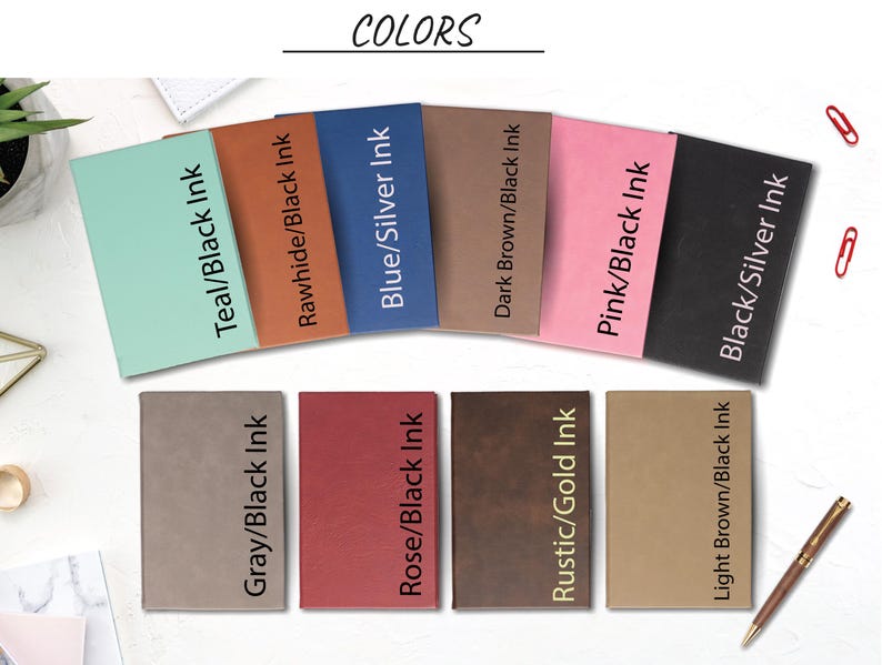 May include: A selection of eight different colored notebooks with various ink colors. The notebooks are arranged in two rows of four. The colors include teal, rawhide, blue, dark brown, pink, black, gray, rose, rustic, and light brown.