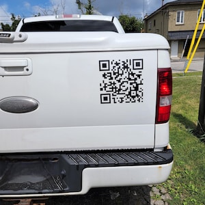 May include: A white pickup truck with a black QR code sticker on the back.
