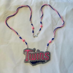 May include: A beaded necklace with a silver chain and a pink and blue beaded pendant that says "Twins".