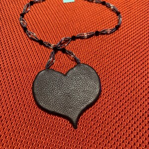 May include: A black leather heart pendant necklace with a black and silver beaded chain.