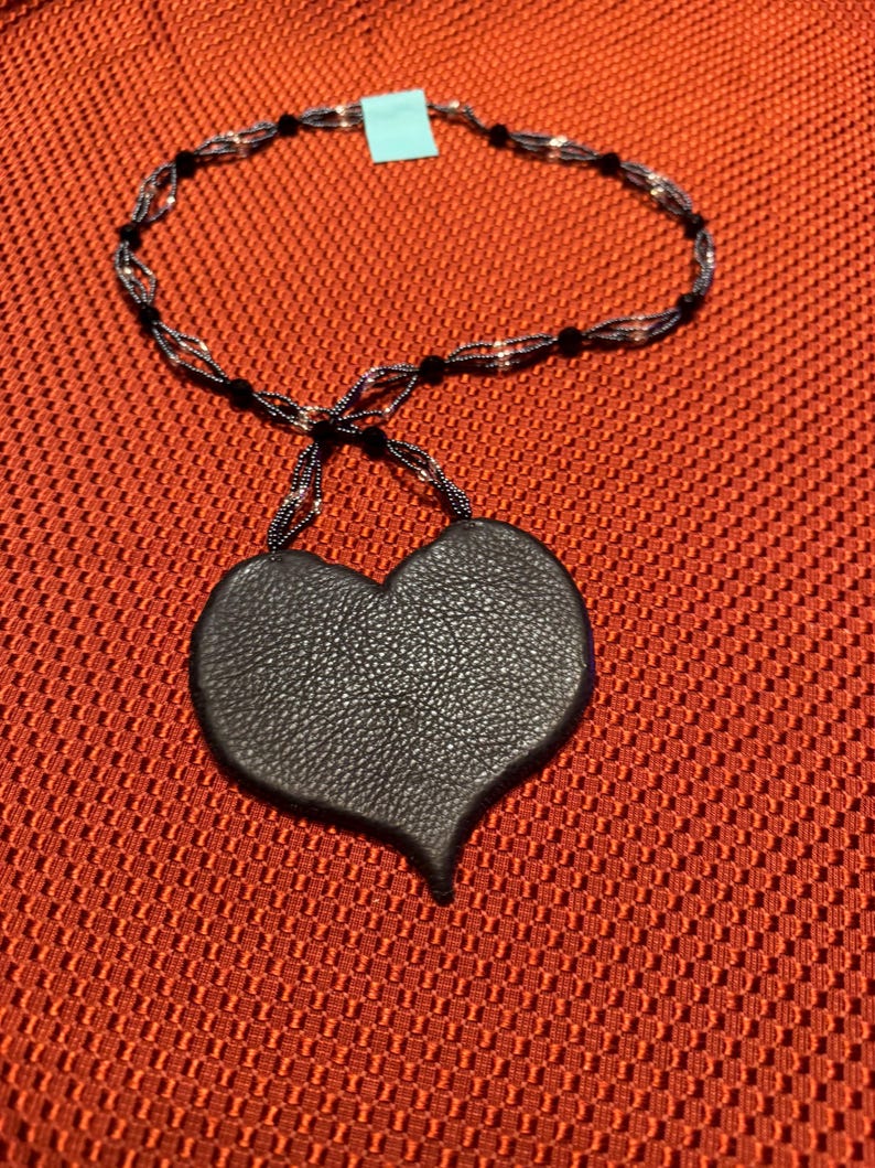 May include: A black leather heart pendant necklace with a black and silver beaded chain.