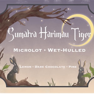 May include: A whimsical illustration of a coffee bag with a crescent moon and two rabbits. The bag is labeled "Sumatra Harimau Tiger Microlot + Wet-Hulled Lemon - Dark Chocolate - Pine".
