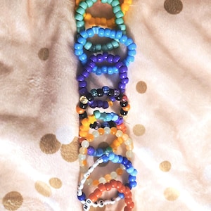 May include: A set of colourful beaded bracelets with different patterns and designs. Some bracelets have words spelled out on them, including "Girl Kisser" and "Moon Sister".