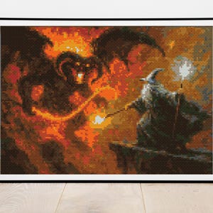 May include: Framed cross-stitch art depicting a wizard facing a fiery demon. The wizard, in a gray robe and hat, holds a staff with a glowing orb. The demon is dark with fiery details, set against an orange and brown background.