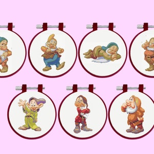 May include: Seven round embroidery hoops with white fabric and colourful cross-stitch images of the seven dwarfs from the Disney movie Snow White and the Seven Dwarfs.