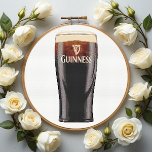 Pu&ograve; includere: Un disegno a punto croce con una pinta di Guinness, con il nome del marchio in lettere bianche. Il disegno &egrave; racchiuso in un telaio di legno ed &egrave; circondato da una ghirlanda di rose bianche e foglie verdi.