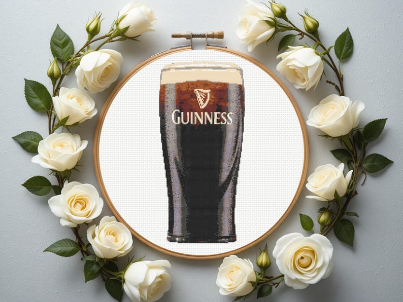 Pu&ograve; includere: Un disegno a punto croce con una pinta di Guinness, con il nome del marchio in lettere bianche. Il disegno &egrave; racchiuso in un telaio di legno ed &egrave; circondato da una ghirlanda di rose bianche e foglie verdi.