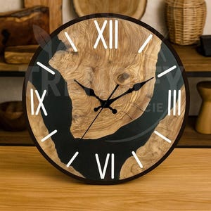 May include: A round wooden wall clock with a dark brown frame. The clock face features a natural wood grain design with black resin accents and white Roman numerals. The clock hands are black.