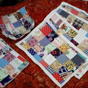 May include: Set of six patchwork placemats in various colors and patterns, including red, blue, green, and white. The placemats are made of fabric scraps sewn together in a grid pattern.