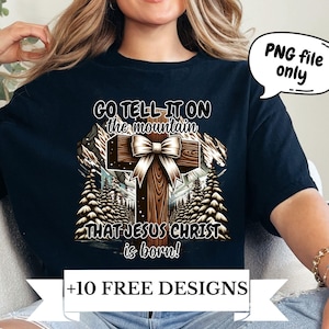 May include: A black t-shirt with a graphic design of a wooden cross with a brown bow on top. The text "GO TELL IT ON THE MOUNTAIN THAT JESUS CHRIST IS BORN!" is printed on the shirt. The text "+10 FREE DESIGNS" is printed on a white banner below the graphic.