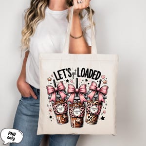 May include: A white canvas tote bag with the text "LET'S get LOADED" in black. Three pink bow-topped cups with the text "Loaded Tea" are depicted in front of the text. The cups have a leopard print design.