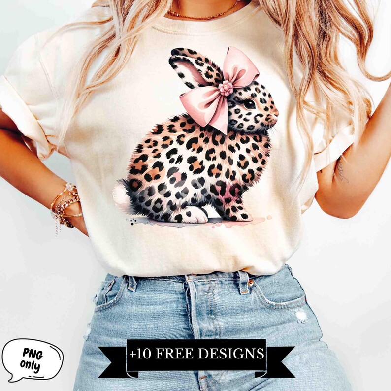 May include: A white t-shirt with a graphic of a leopard print bunny wearing a pink bow. The text " +10 FREE DESIGNS" is printed on the bottom of the shirt.