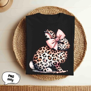 May include: Black t-shirt with a graphic of a leopard print bunny wearing a pink bow.