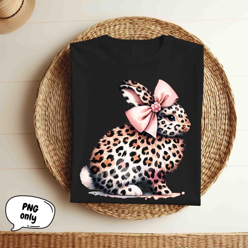 May include: Black t-shirt with a graphic of a leopard print bunny wearing a pink bow.