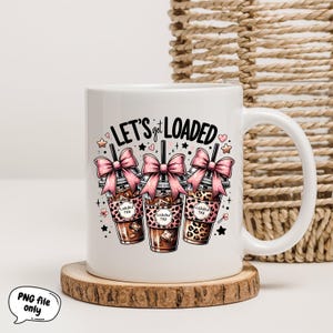 May include: White ceramic mug with a black and pink design. The mug features three cartoon iced coffee cups with pink bows and the text "Let's get loaded".
