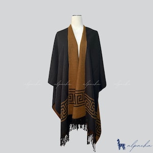 May include: A black and brown poncho with a geometric design on the bottom edge and a fringed hem. The poncho is displayed on a mannequin. The inner layer is brown, and the outer layer is black.