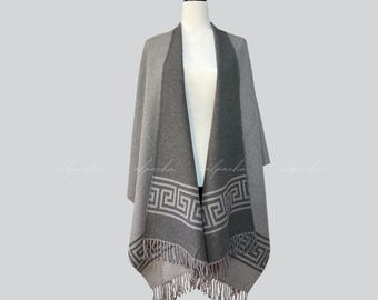 May include: Grey alpaca wool poncho with a geometric pattern and fringe trim. The poncho is reversible, with a grey side and a darker grey side.