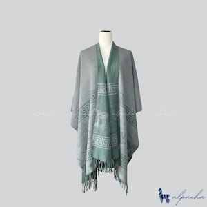 Puede incluir: Un poncho de lana de alpaca gris y verde con un patrón geométrico y flecos.