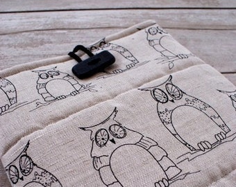 May include: A beige fabric kitchen towel with a black and white owl design. The towel has a black plastic button closure.