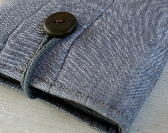 May include: A gray fabric journal cover with a wooden button closure. The cover has a quilted design with wavy lines.