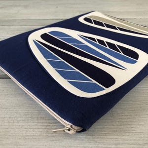 Op de afbeelding: Marineblauwe etui met ritssluiting en een abstract ontwerp in wit, blauw en grijs. De etui heeft een rechthoekige vorm, een ritssluiting en een patroon op de voorkant.