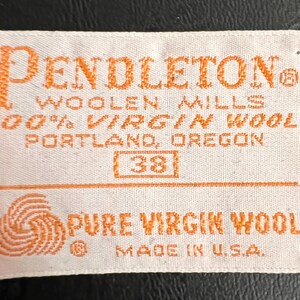 May include: A white label with orange text that reads "PENDLETON WOOLEN MILLS 100% VIRGIN WOOL PORTLAND, OREGON 38 PURE VIRGIN WOOL MADE IN U.S.A."