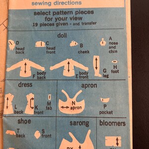 May include: A blue and white sewing pattern guide for Simplicity pattern number 6063. The pattern includes instructions for making a doll, dress, apron, shoe, sarong, and bloomers. The pattern pieces are labeled with letters and names.