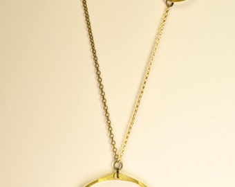 May include: A gold necklace with two circular pendants and a strand of red beads. The larger pendant has a series of gold teardrop shapes hanging from it.